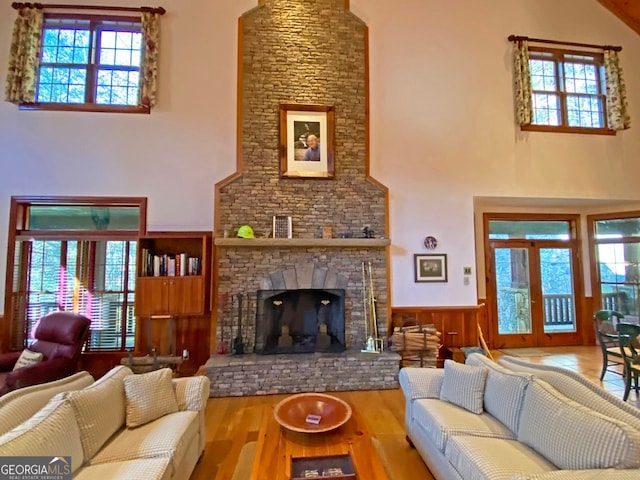 living room with a healthy amount of sunlight, a high ceiling, light wood-type flooring, and a fireplace