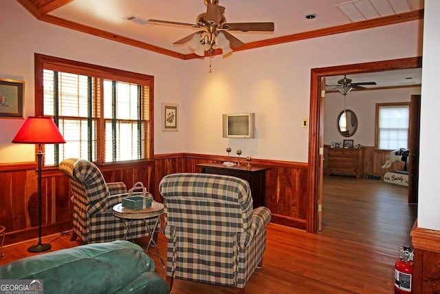 living area with ceiling fan, crown molding, and dark hardwood / wood-style flooring