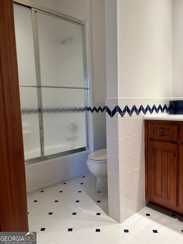 bathroom with toilet, tile walls, and tile flooring