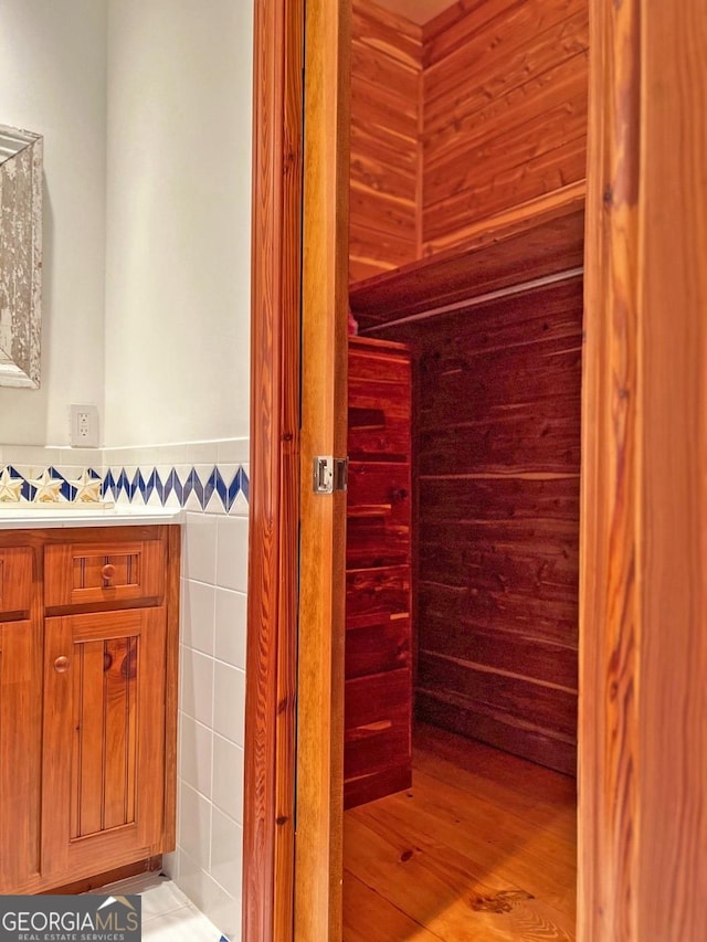 bathroom with vanity, wood-type flooring, and tile walls