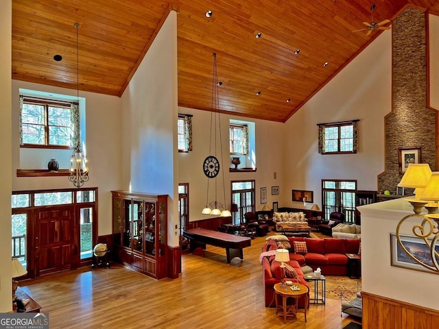 living room featuring high vaulted ceiling, light hardwood / wood-style floors, ceiling fan with notable chandelier, and wooden ceiling