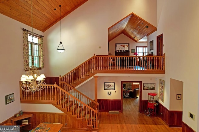 staircase with high vaulted ceiling, wood ceiling, a chandelier, and hardwood / wood-style flooring