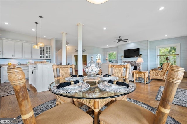 dining area with a healthy amount of sunlight, hardwood / wood-style floors, a brick fireplace, and ceiling fan