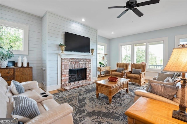 living room with plenty of natural light, a brick fireplace, ceiling fan, and wood-type flooring