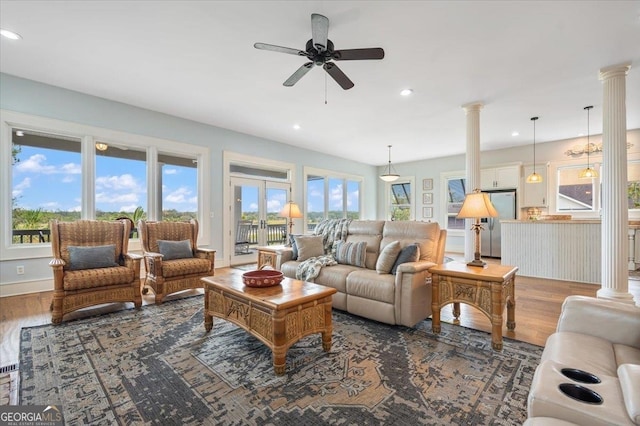 living room with dark hardwood / wood-style flooring, ceiling fan, and ornate columns