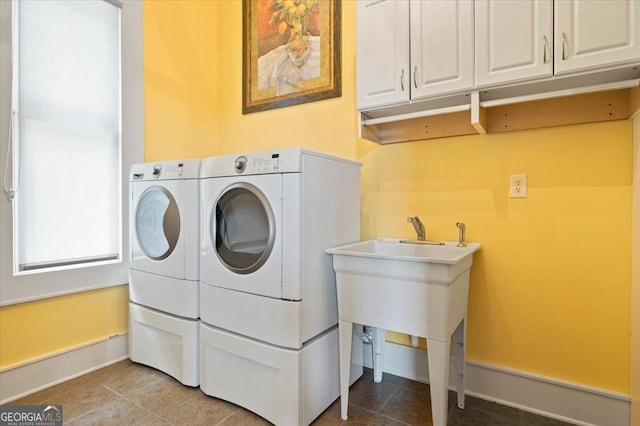 laundry room featuring washing machine and clothes dryer, cabinets, and light tile floors