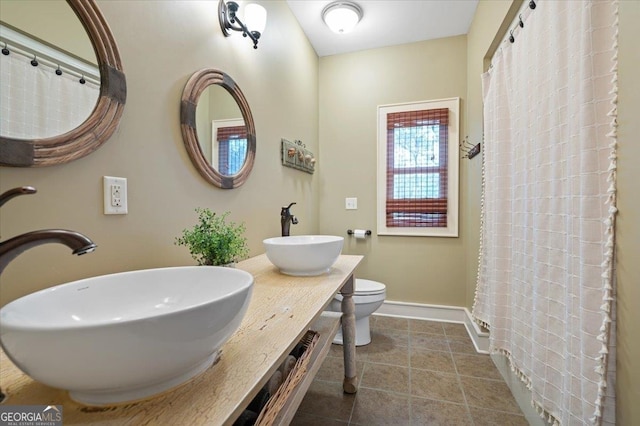 bathroom with dual sinks, tile flooring, toilet, and large vanity