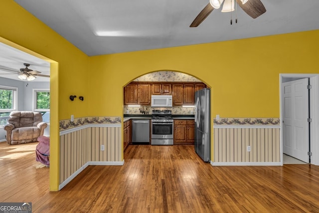 805 Quail Cove Cir, Warne, NC 28909 - kitchen with stainless steel appliances, ceiling fan, wood-type flooring, a wainscoted wall, and brown cabinetry