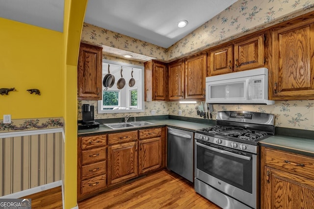 805 Quail Cove Cir, Warne, NC 28909 - kitchen with stainless steel appliances, wallpapered walls, dark countertops, light wood-type flooring, and brown cabinets