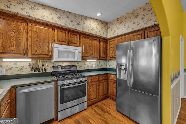 805 Quail Cove Cir, Warne, NC 28909 - kitchen with stainless steel appliances, brown cabinetry, light wood-style flooring, and wallpapered walls