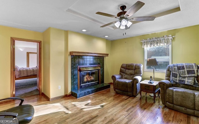 living room featuring a fireplace, light wood-type flooring, and ceiling fan