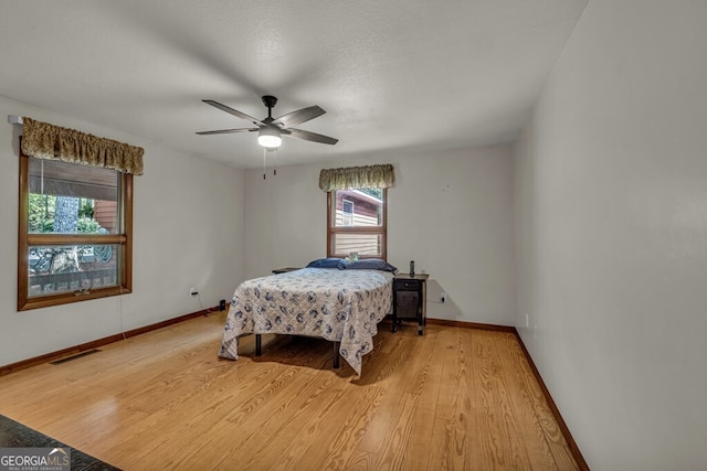 805 Quail Cove Cir, Warne, NC 28909 - bedroom featuring multiple windows, light wood-type flooring, baseboards, and ceiling fan