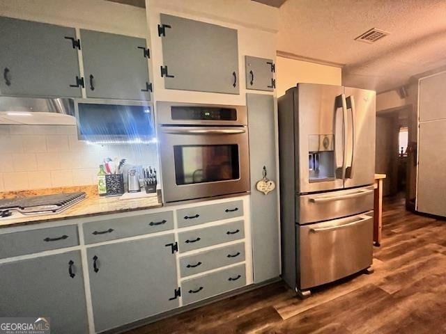 kitchen featuring gray cabinetry, exhaust hood, decorative backsplash, a textured ceiling, and stainless steel appliances