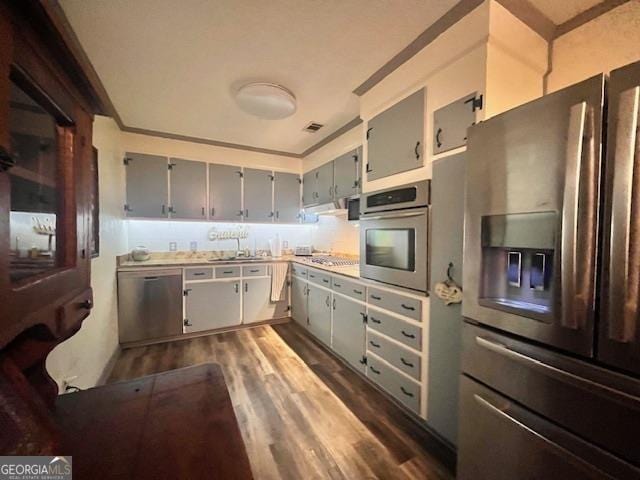 kitchen featuring appliances with stainless steel finishes, ventilation hood, dark wood-type flooring, sink, and gray cabinets