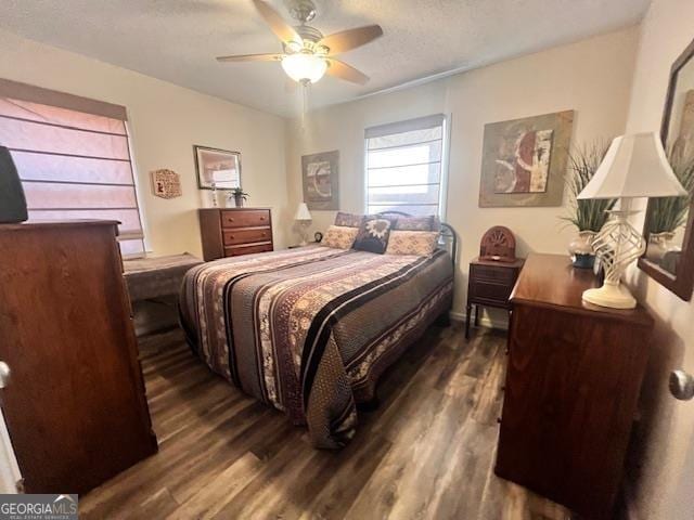 bedroom with a textured ceiling, ceiling fan, and dark hardwood / wood-style floors