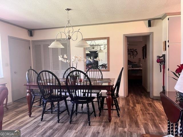 dining space featuring a textured ceiling, dark wood-type flooring, and a notable chandelier