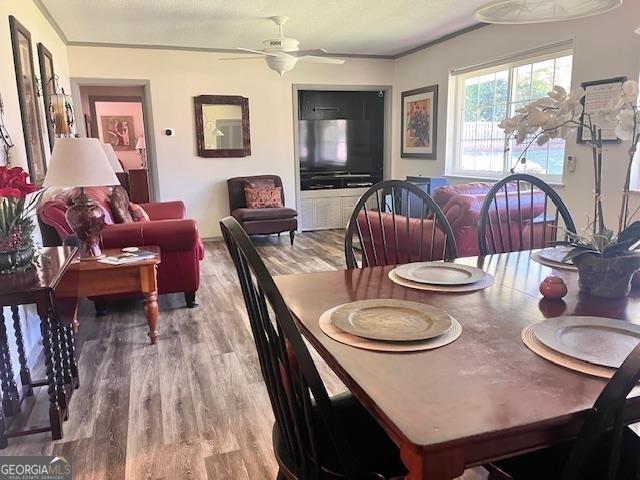 dining room with ceiling fan, crown molding, and wood-type flooring