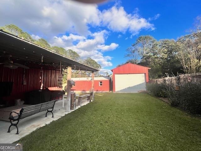 view of yard featuring a patio area, an outbuilding, and a garage