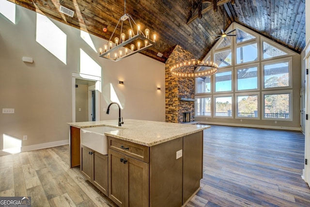 kitchen featuring ceiling fan with notable chandelier, sink, high vaulted ceiling, and light hardwood / wood-style flooring