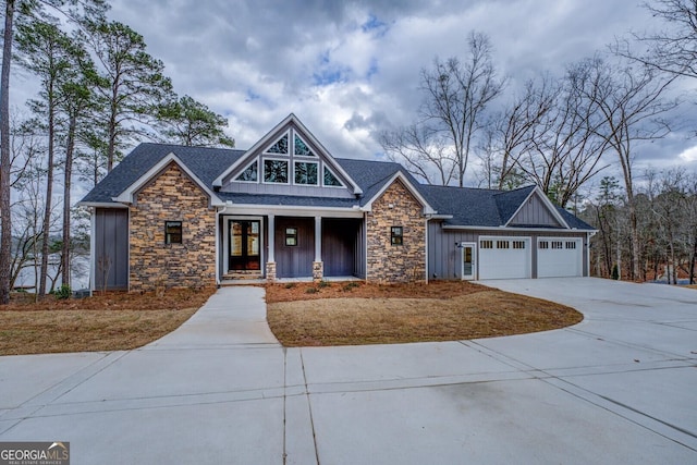 craftsman-style home with stone siding, covered porch, board and batten siding, and driveway