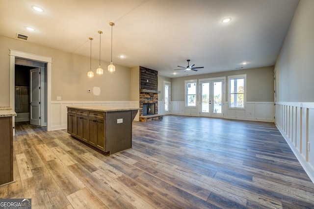 kitchen with pendant lighting, dark hardwood / wood-style floors, a stone fireplace, and ceiling fan