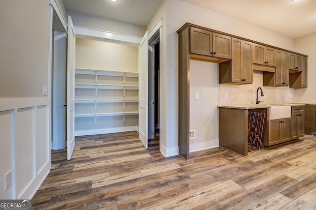 kitchen with backsplash, light stone countertops, dark hardwood / wood-style flooring, and sink