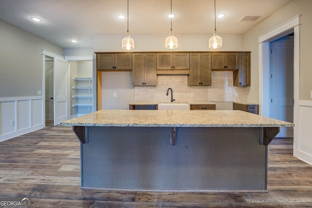 kitchen featuring decorative light fixtures, dark hardwood / wood-style flooring, and light stone countertops