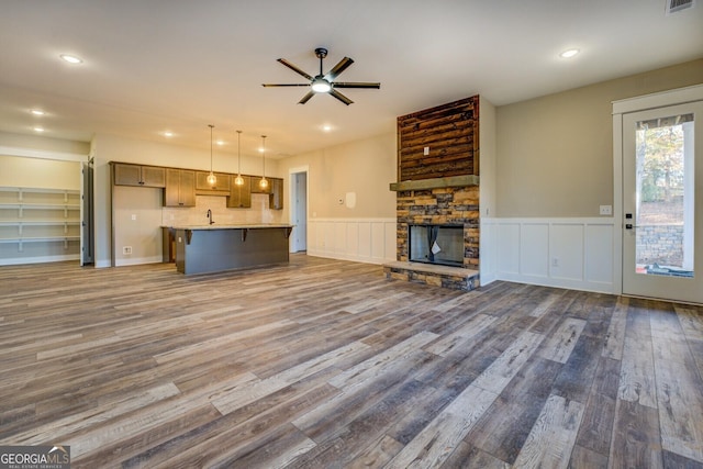 unfurnished living room featuring ceiling fan, a fireplace, dark wood-type flooring, and sink