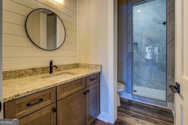 bathroom featuring wood-type flooring, toilet, a shower with shower door, and wood walls