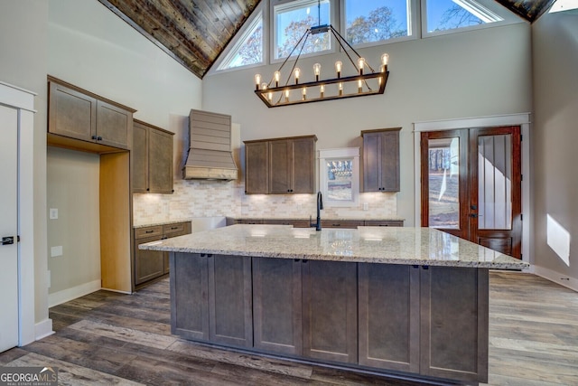 kitchen featuring light stone countertops, plenty of natural light, high vaulted ceiling, and custom range hood