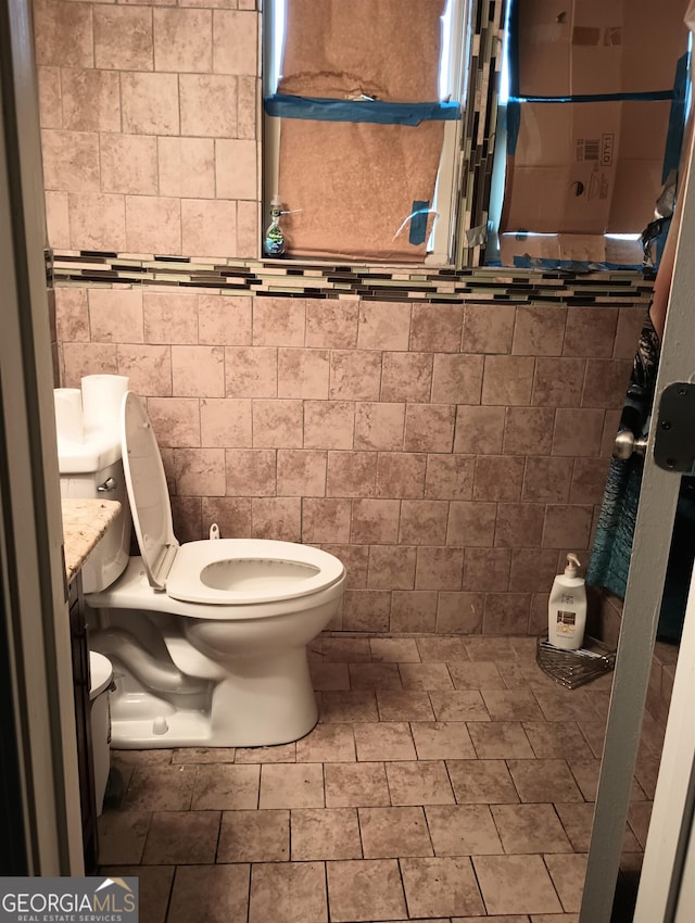 bathroom with tile patterned flooring, toilet, vanity, and tile walls