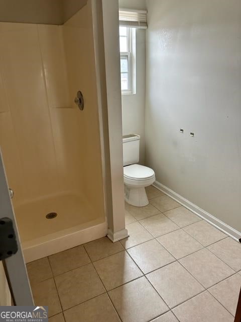 bathroom with a shower, toilet, and tile patterned floors