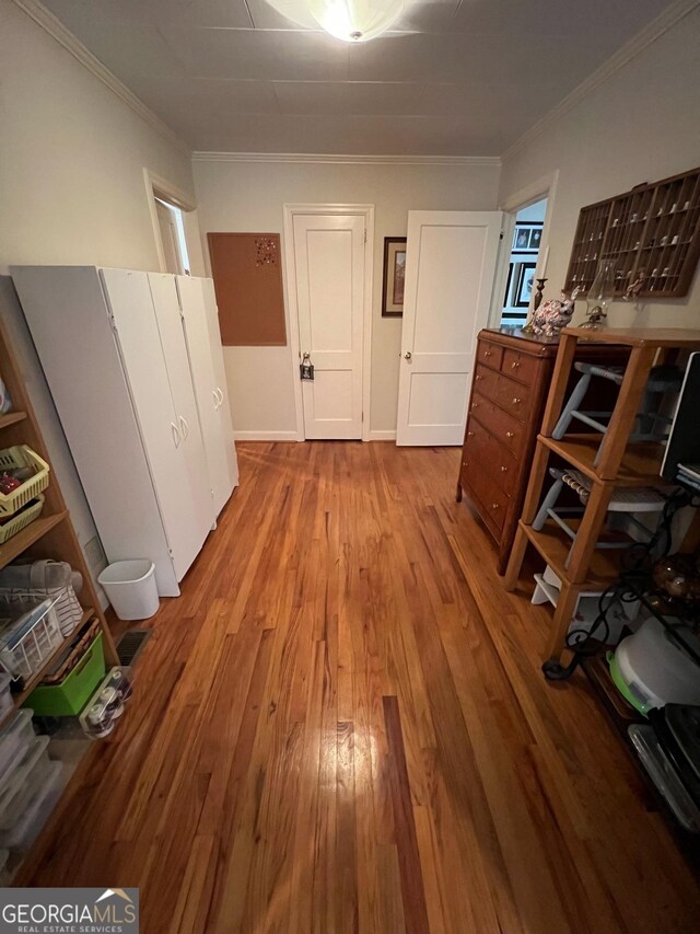 hall featuring ornamental molding, baseboards, and wood finished floors