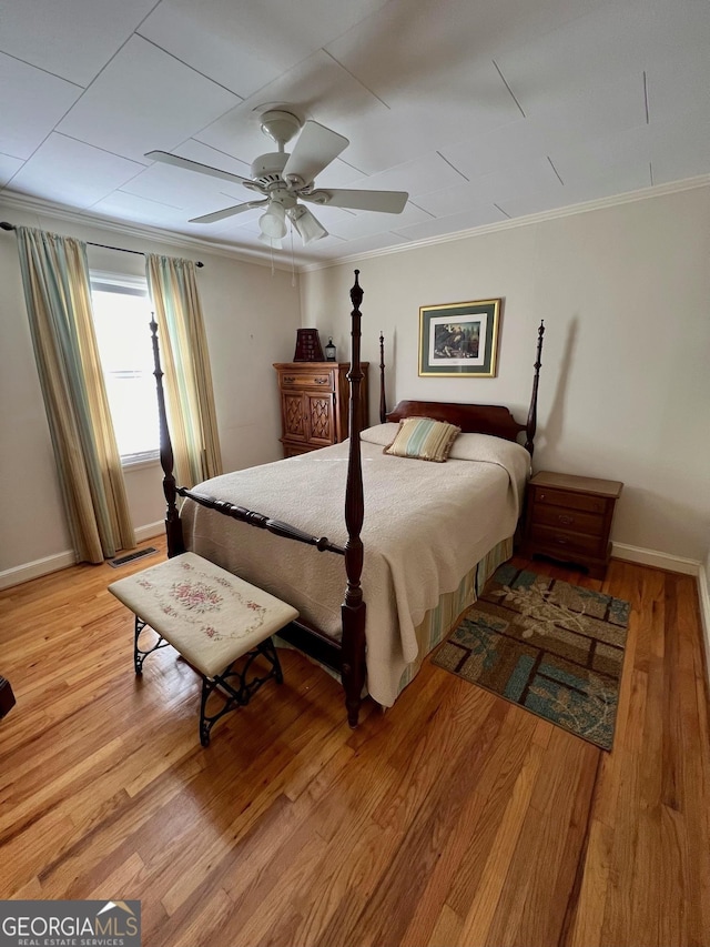 bedroom with light wood-style floors, baseboards, ornamental molding, and ceiling fan