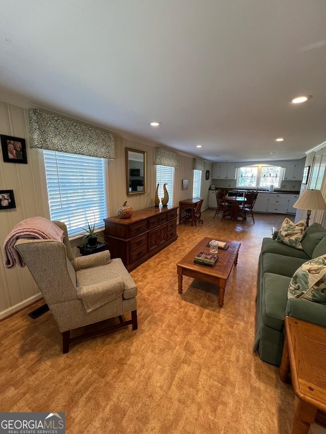 living room with light carpet, a decorative wall, visible vents, and recessed lighting