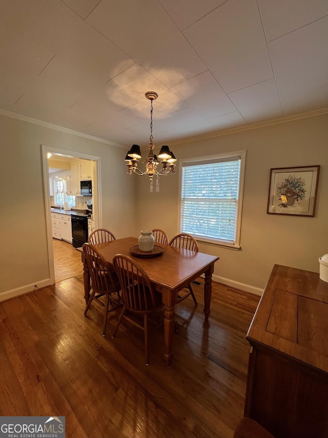 dining area with baseboards, ornamental molding, dark wood finished floors, and an inviting chandelier