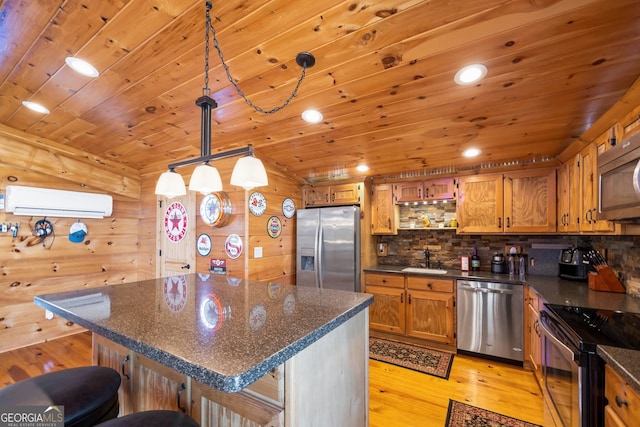 kitchen featuring pendant lighting, a breakfast bar area, light hardwood / wood-style floors, stainless steel appliances, and wood walls