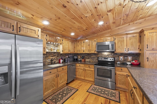 kitchen featuring sink, light hardwood / wood-style floors, stainless steel appliances, vaulted ceiling, and tasteful backsplash