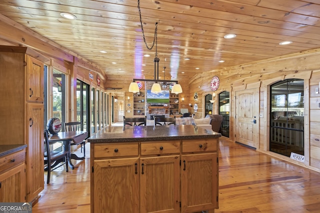 kitchen featuring a kitchen island, pendant lighting, wood walls, and light hardwood / wood-style floors