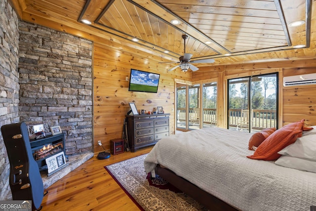 bedroom with wooden walls, wood-type flooring, wood ceiling, and a fireplace