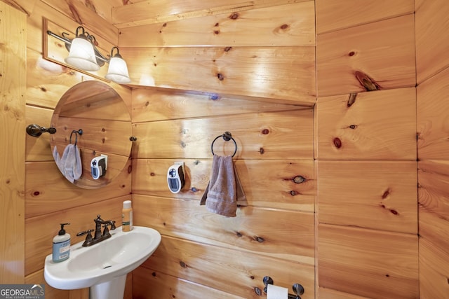 bathroom featuring wood walls and sink