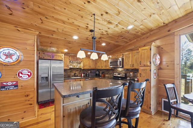 kitchen featuring a kitchen island, hanging light fixtures, appliances with stainless steel finishes, and light hardwood / wood-style flooring