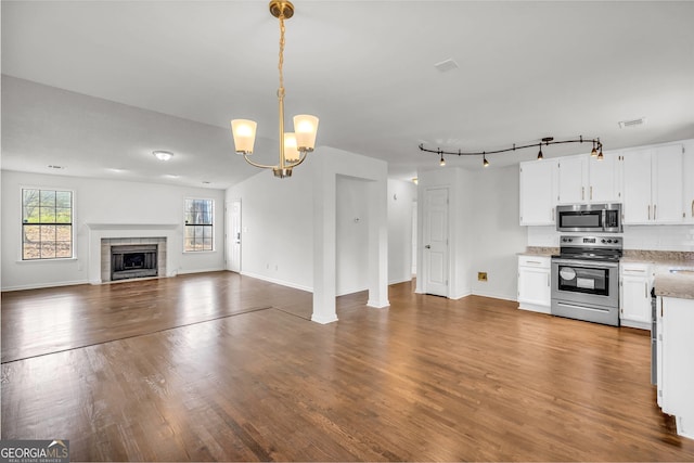 kitchen with appliances with stainless steel finishes, hardwood / wood-style floors, a chandelier, and white cabinets