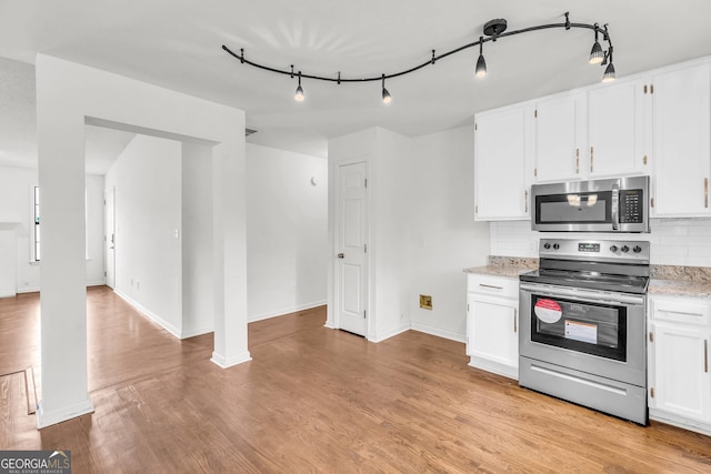 kitchen with appliances with stainless steel finishes, light hardwood / wood-style floors, white cabinets, rail lighting, and tasteful backsplash