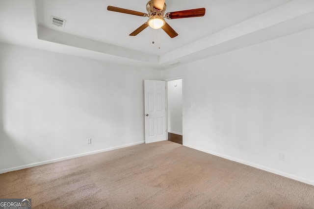 carpeted spare room featuring ceiling fan and a tray ceiling