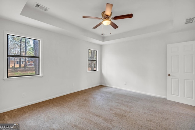 spare room with carpet floors, a tray ceiling, and ceiling fan