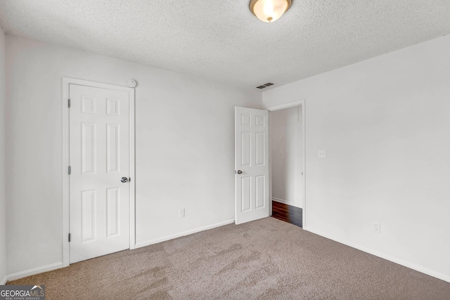 unfurnished bedroom featuring a textured ceiling and dark colored carpet