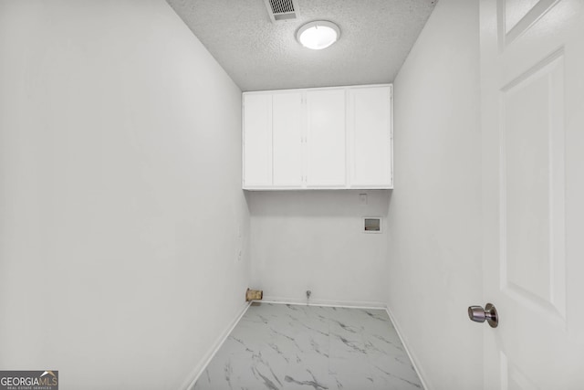 washroom with washer hookup, a textured ceiling, cabinets, and light tile floors