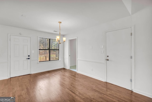 unfurnished room with an inviting chandelier and dark wood-type flooring