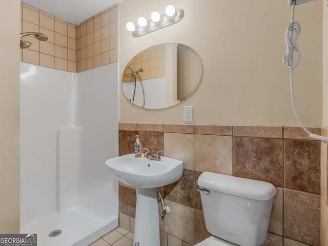 bathroom featuring tile walls, toilet, and a tile shower